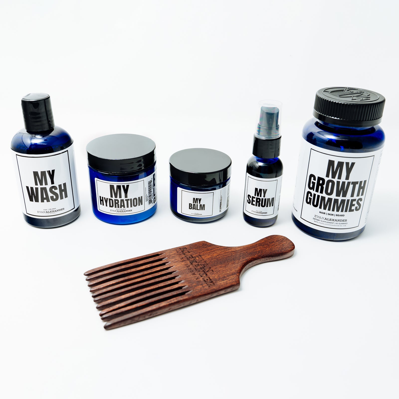 A set of beard care products including bottles, jars, and a wooden comb laid out on a white surface.