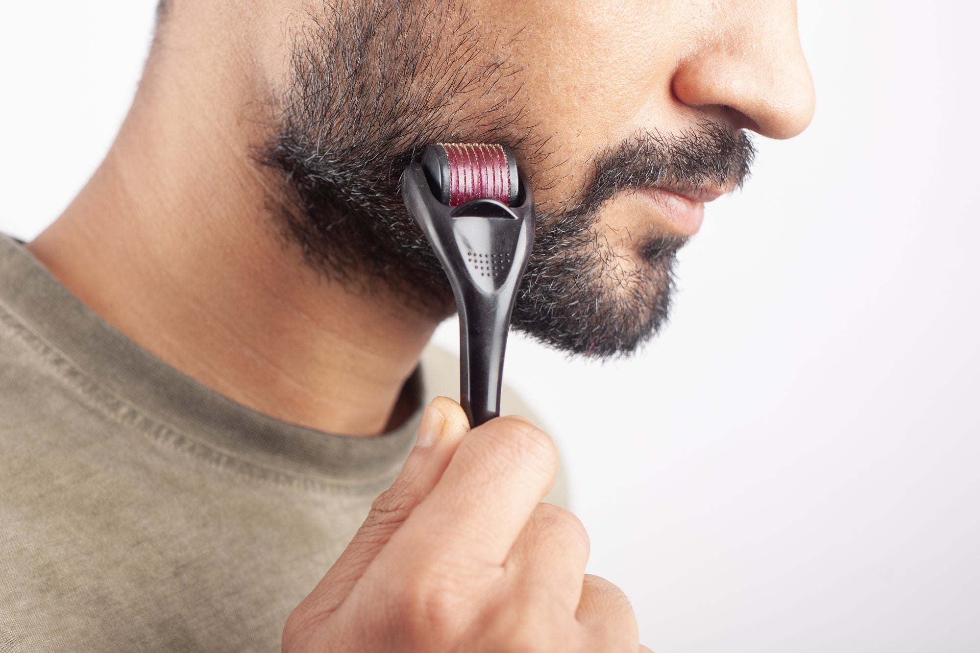 A confident man in his late twenties with a beard, showcasing the results of using a derma roller for beard growth.